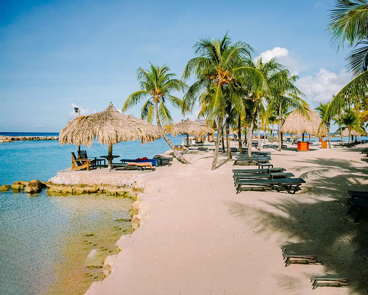 Strandbedden en parasols op Mambo Beach, Curaçao